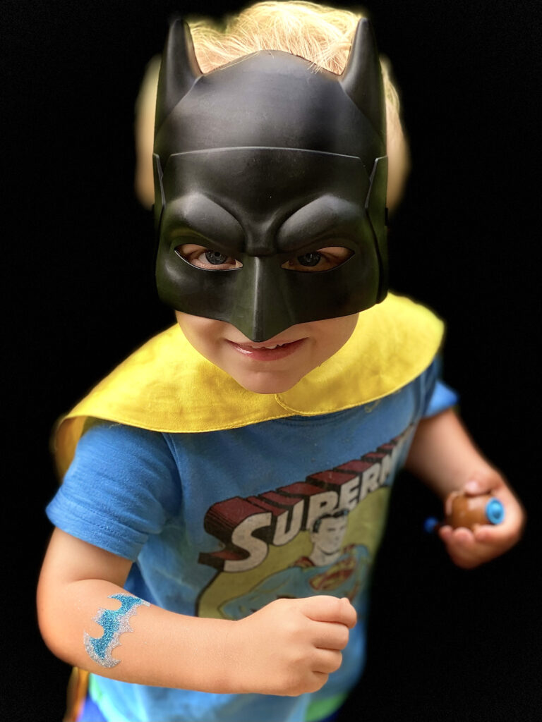 Boy dressed as superhero with Batman glitter tattoo