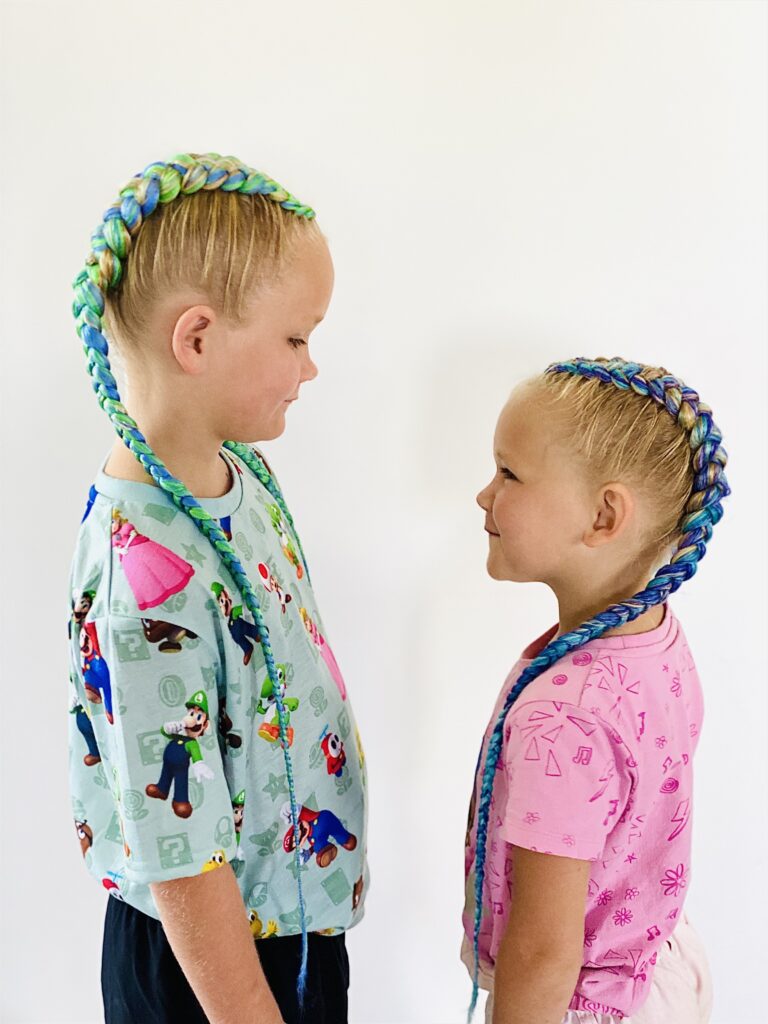 Two sisters with colourful braids looking at each other